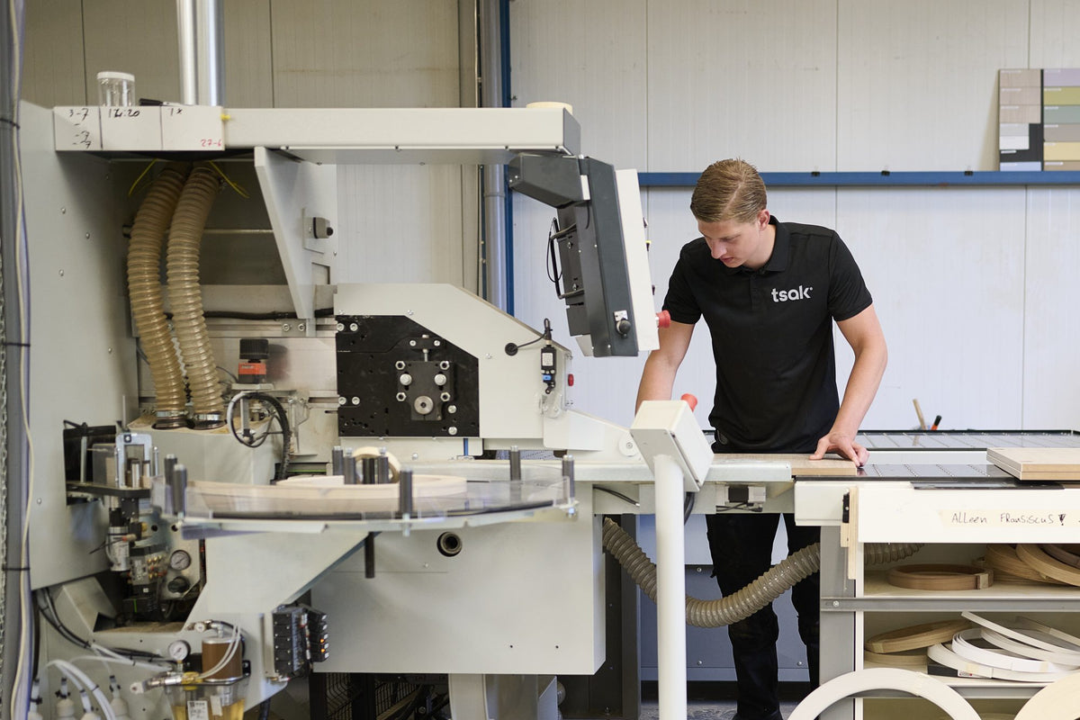 Tsak-medewerker bij de kantenplakmachine in de eigen werkplaats